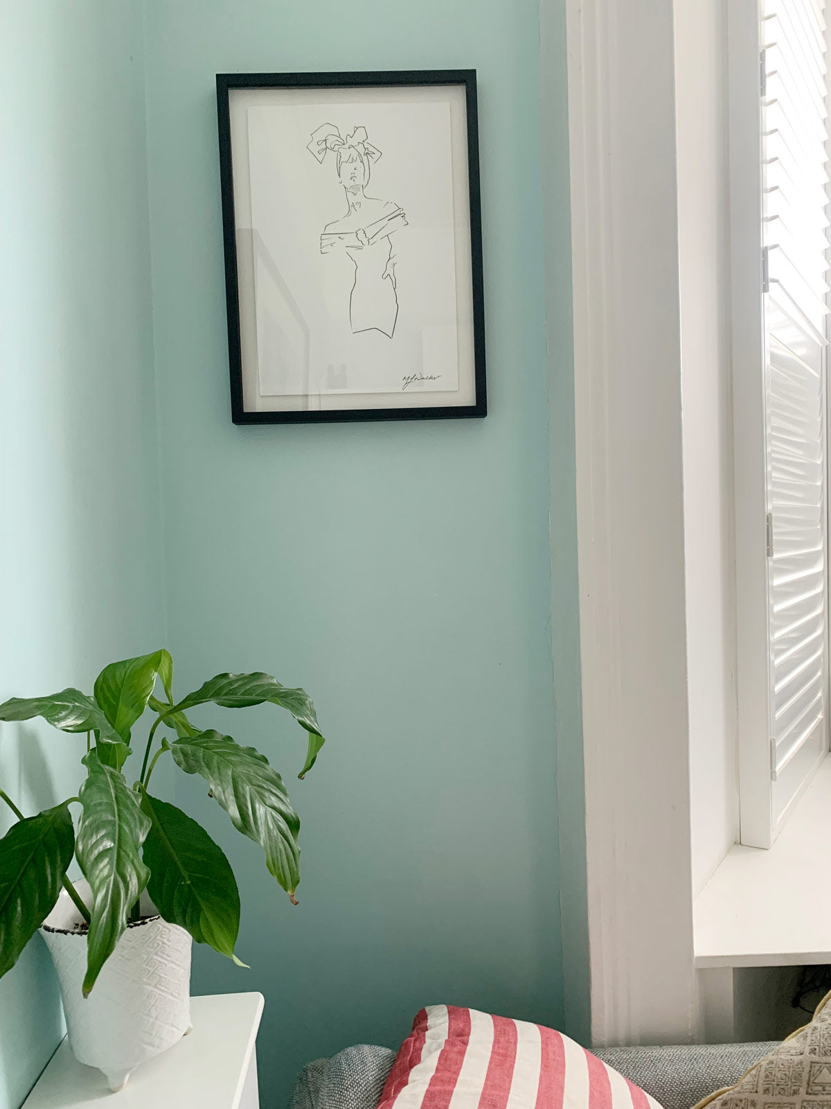 Lady in a headscarf illustration framed. Hanging on a blue wall.